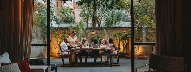 family sits outside around a table to eat a meal