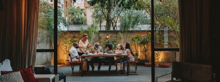 family sits outside around a table to eat a meal